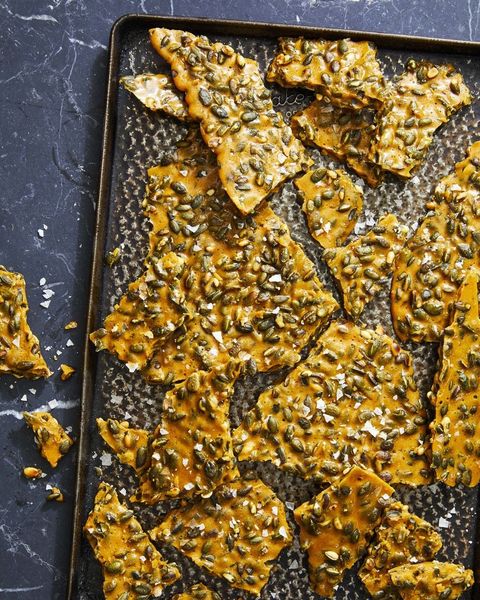 rosemary pumpkin seed brittle broken into pieces on a sheet pan