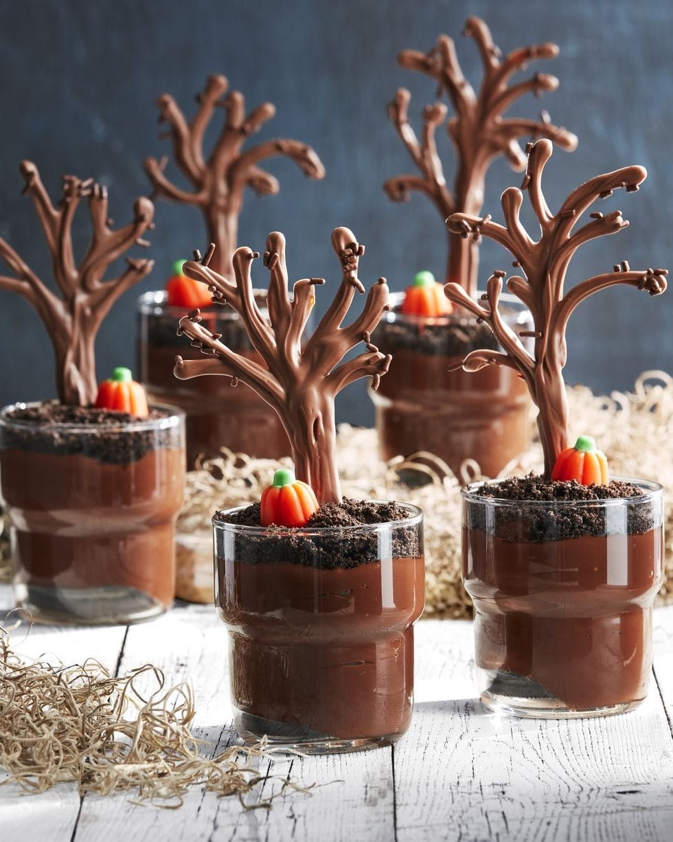 spooky forest pudding cups arranged on a table with little tufts of hay around them