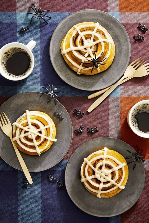 pumpkin spiced buns with spiderweb glaze on individual plates with forks and cups of coffee