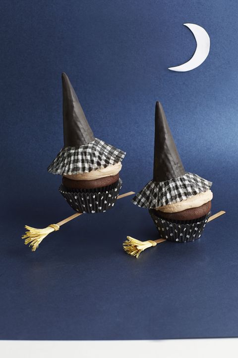 chocolate pumpkin cupcakes with witch hats on top made of ice cream cones and a small paper broom positioned underneath the cupcakes