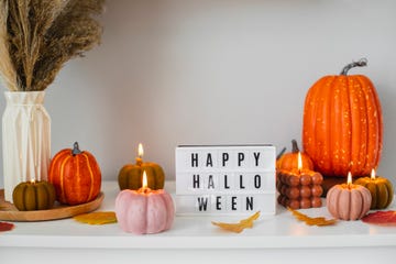 a lightbox with happy halloween on it surrounded by pumpkins and lit pumpkin candles