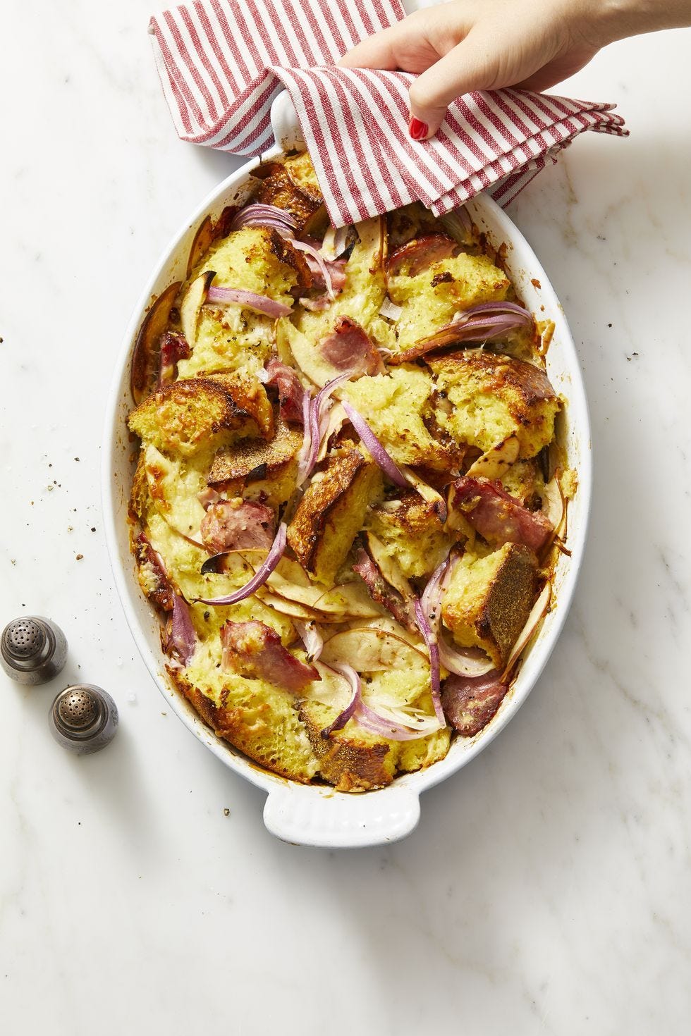 ham, cheddar, and red onion bread pudding in a white baking dish