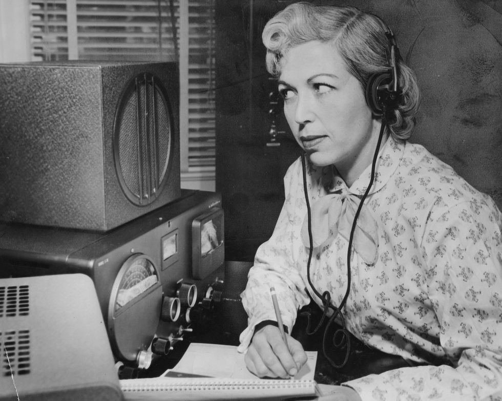 woman uses earphones to listen to ham radio in 1950s