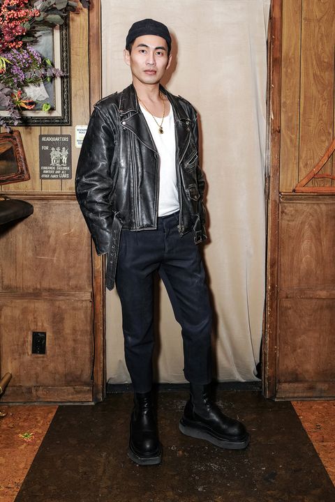 designer han chong of self portrait wears a black motorcycle jacket, a white tee, black pants, and black boots with a platform