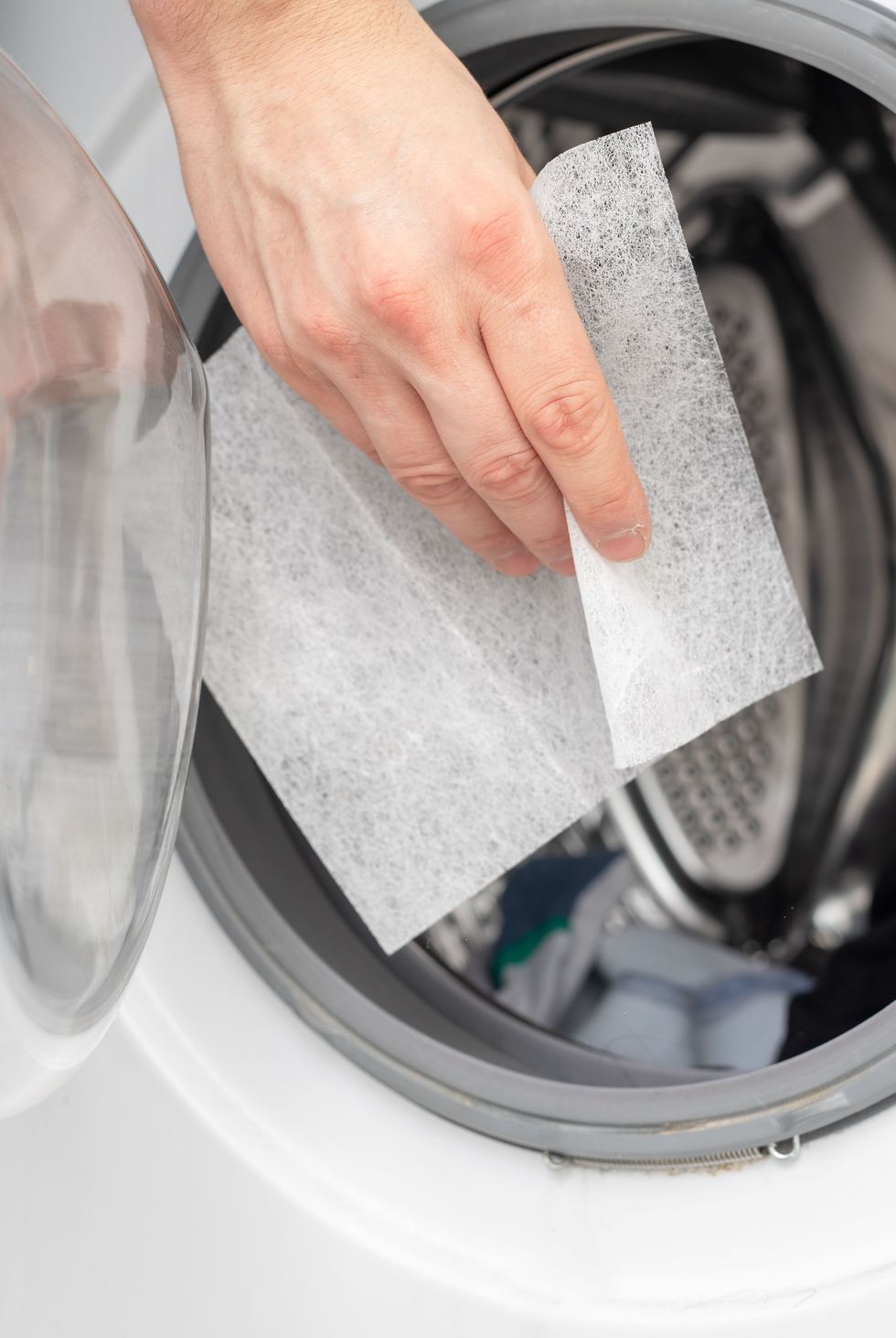 hand dropping dryer aromatic sheets in a washing machine