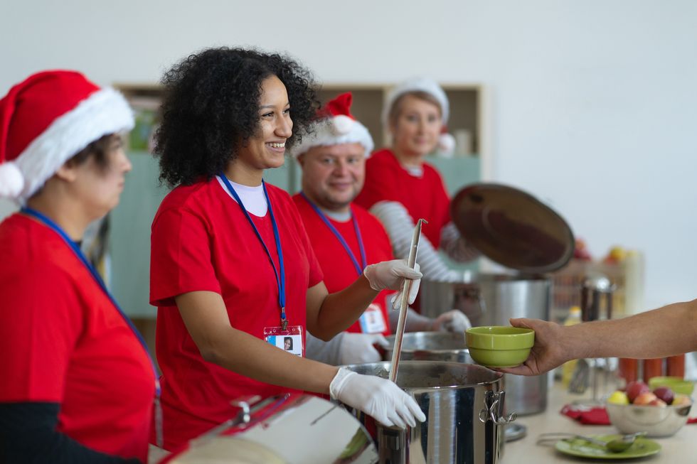 a hand holding a bowl to receive a portion of soup from a smiling volunteer