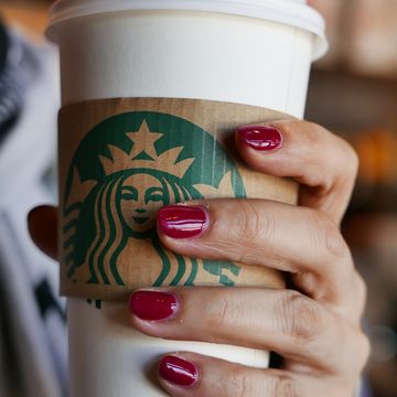 hand holding a coffee cup in a starbucks coffee shop in