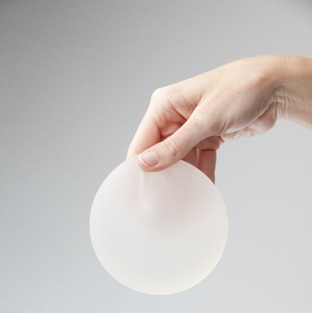 A hand holding a silicone breast implant