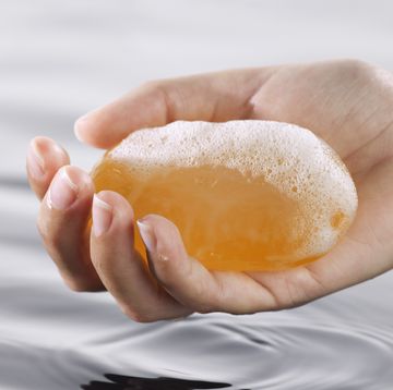 a hand holding a sudsy bar of kojic acid soap