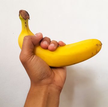 hand holding big banana on white background
