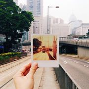 hand holding instant photo picture frame on street