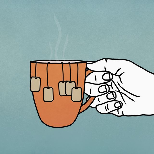 hand holding mug with many tea bags