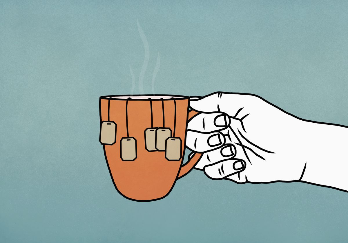 hand holding mug with many tea bags