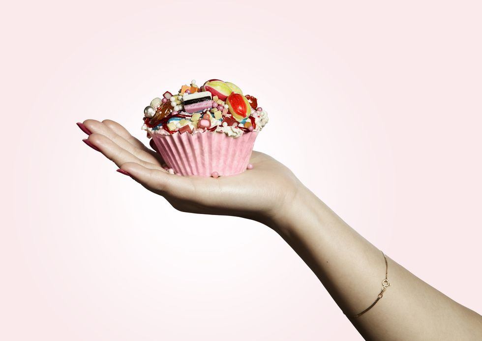 Hand holding pink designed cupcake full of sweets