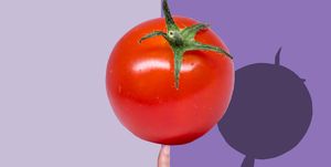 hand holding tomato with a shadow