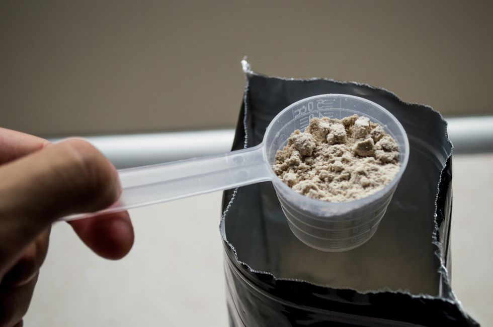 hand measuring whey in a bag of whey protein powder