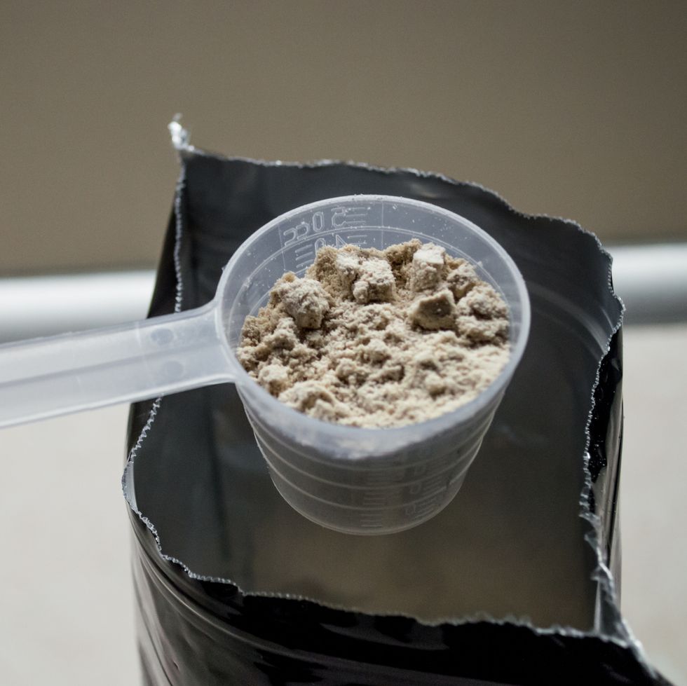 Hand Measuring Whey in a Bag of Whey Protein Powder
