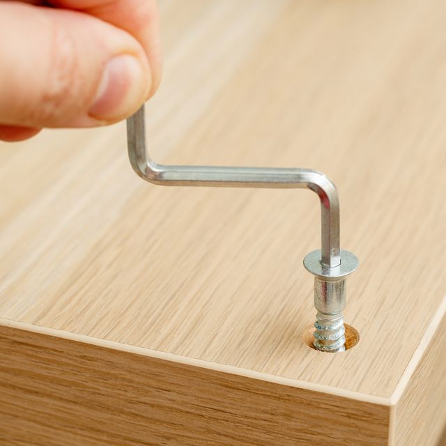 Hand of assembly worker with hexagonal key screwing furniture screw