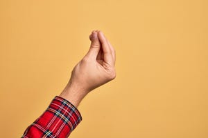 hand of caucasian young man showing fingers over isolated yellow background doing italian gesture with fingers together, communication gesture movement