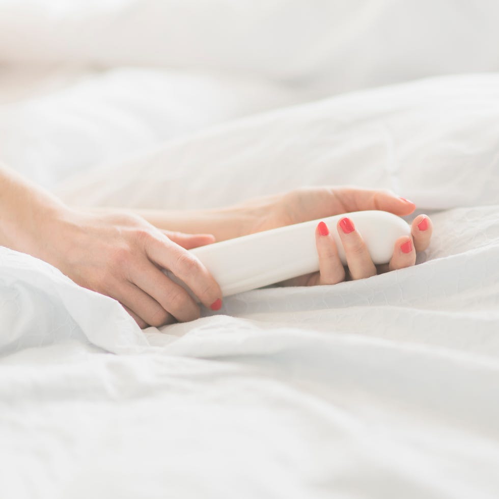 hand of woman holding sex toy in bed