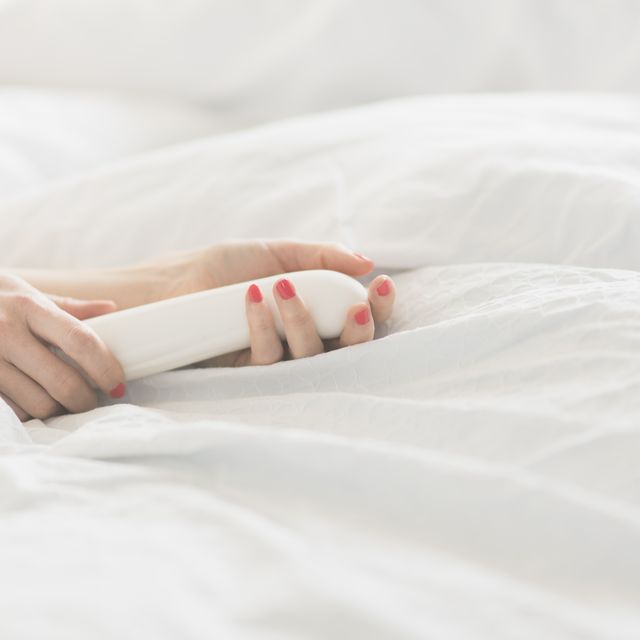 hand of woman holding sex toy in bed