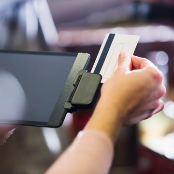 Hand of woman sliding credit card through reader