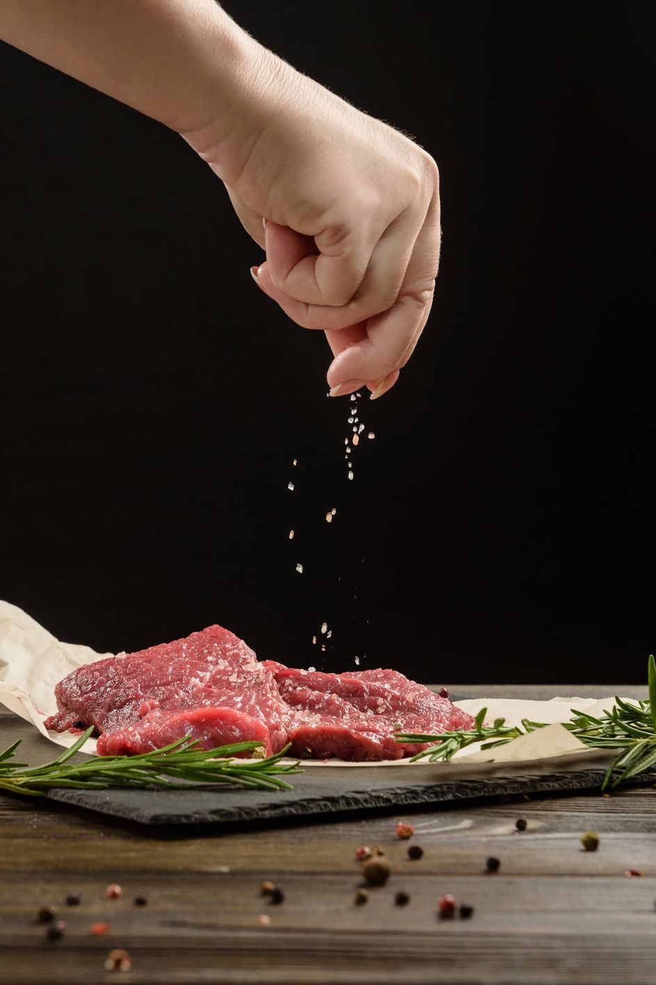 hand sprinkle salt on beef steaks