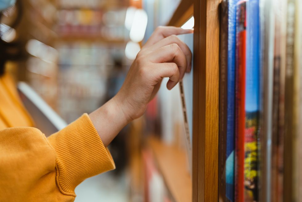 a hand takes out a book from the shelf