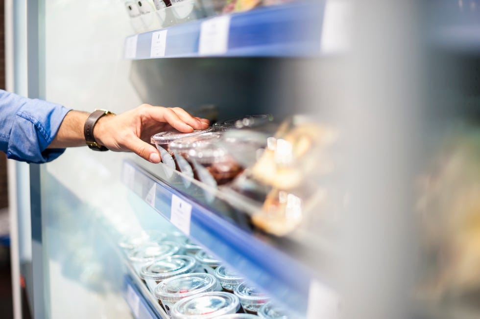hand taking food from cooling shelf