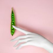 hand touching peas in a pod