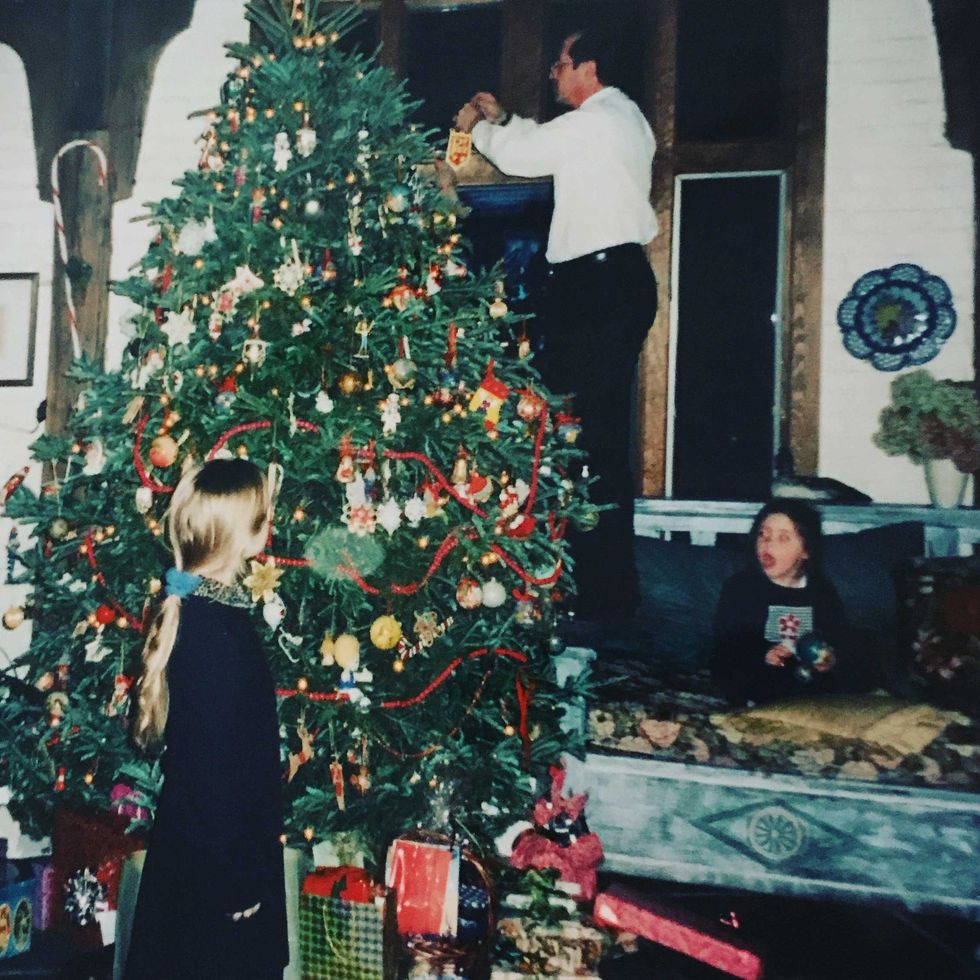 john handler decorates a christmas tree as his daughters watch