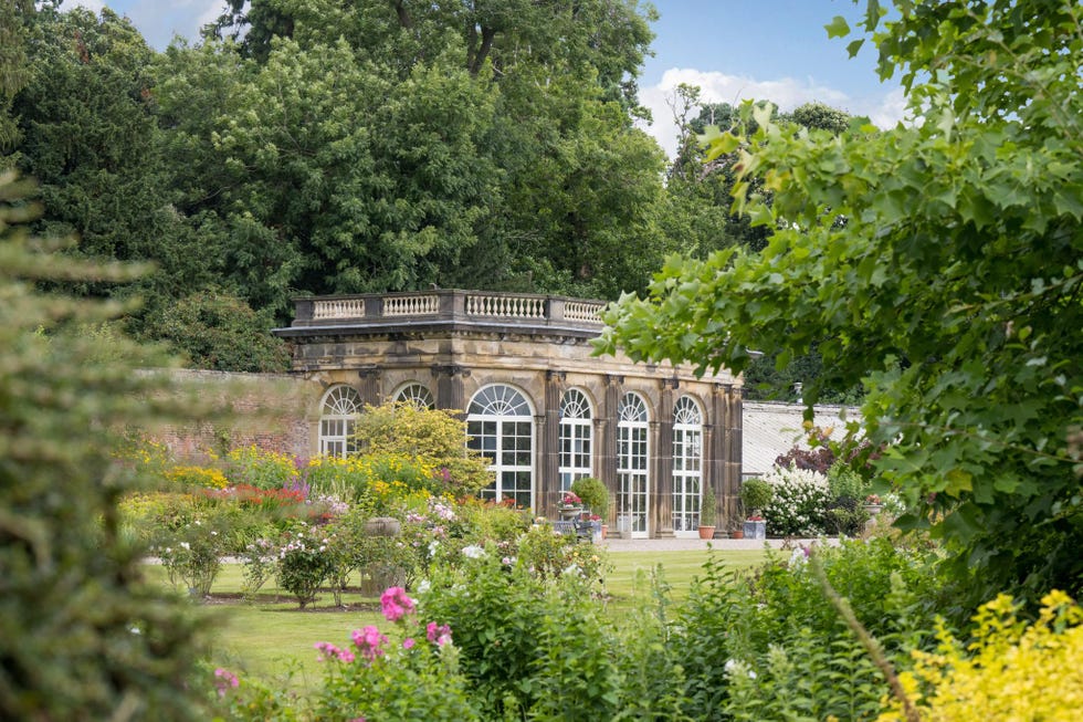 a greenhouse surrounded by a colorful garden