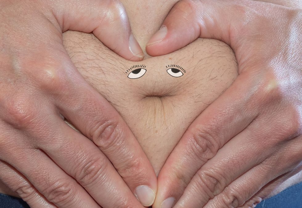 hands as a heart over a fat belly with painted eyes