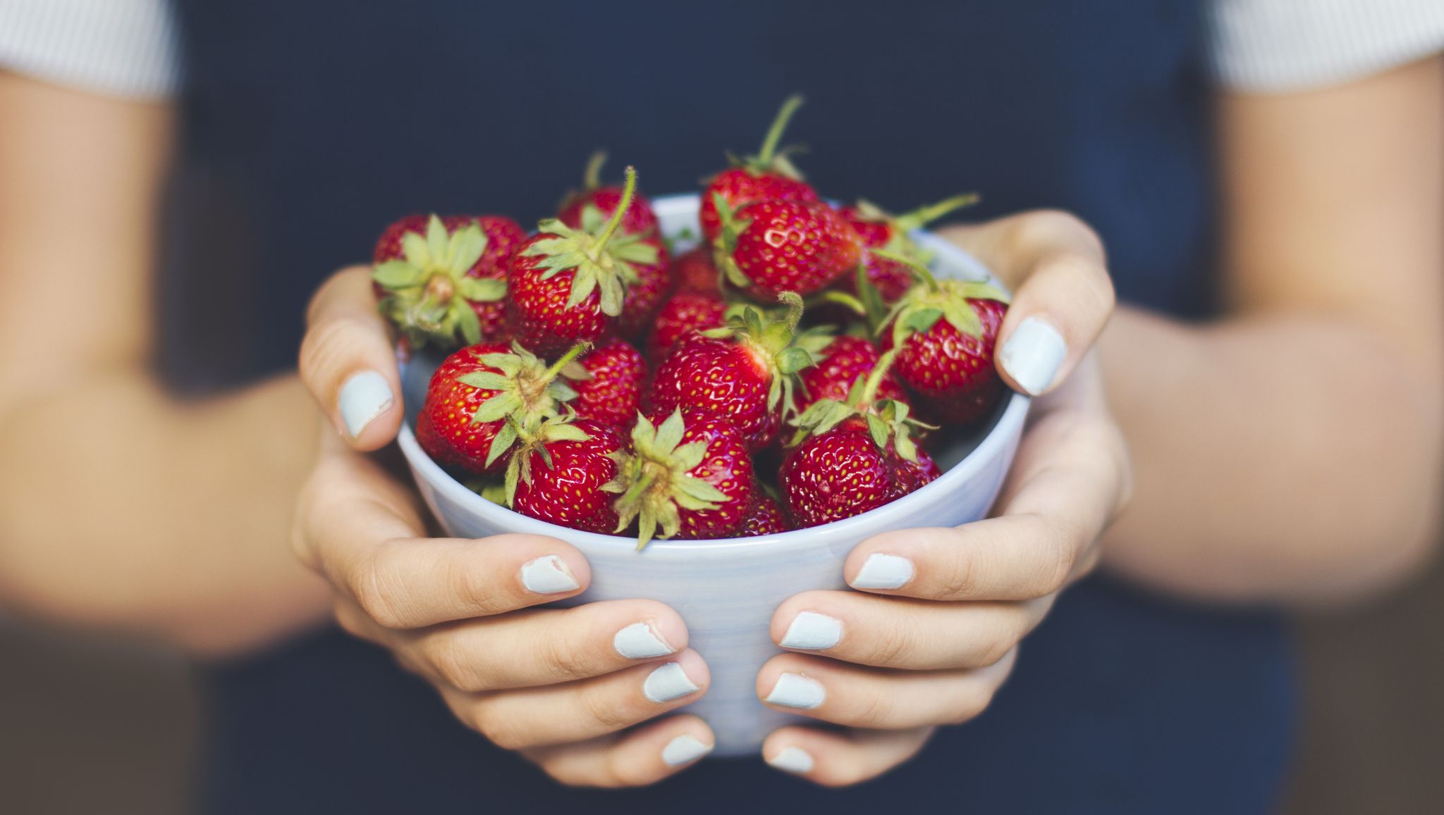 Hands holding bowl of strawberries