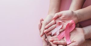 hands holding pink ribbons on pink background, breast cancer awareness and october pink day