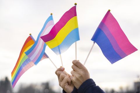 hands holding pride flags in the sky
