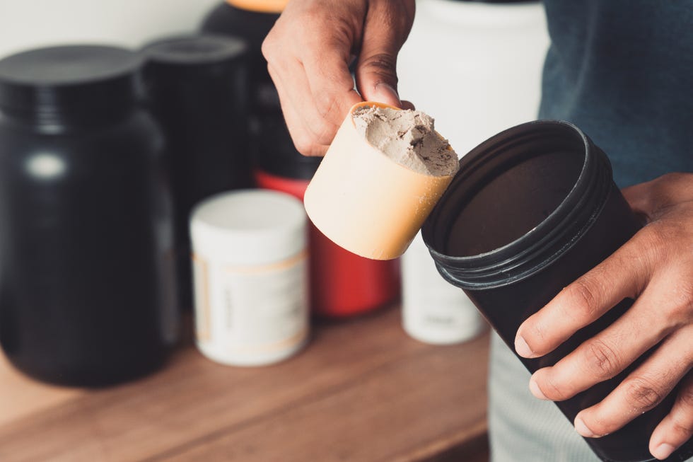 hands holding scoop of whey protein and shaker with copy space healthy life