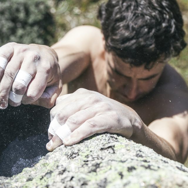 Hands of a climber with sticking plaster and chalk during a boulder climbing