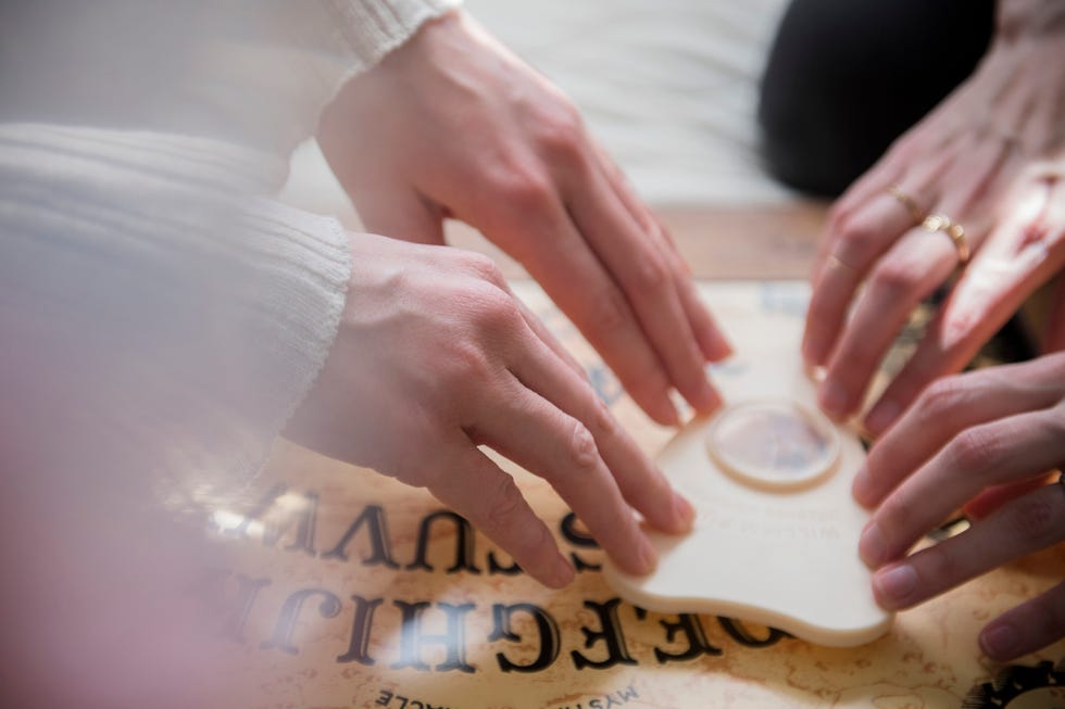 Hands of Caucasian women using a Ouija board hands of caucasian women using a ouija board