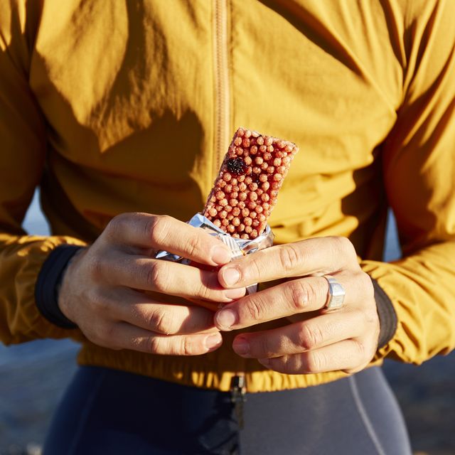 hands of cyclist holding energy bar on sunny day