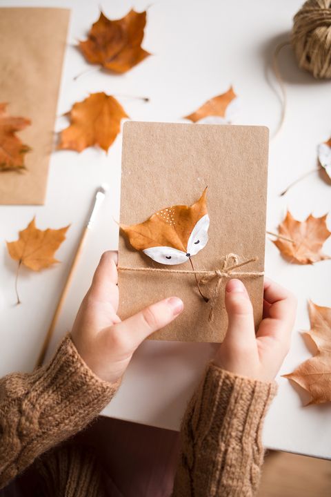 hands of girl holding decorated autumn leaf