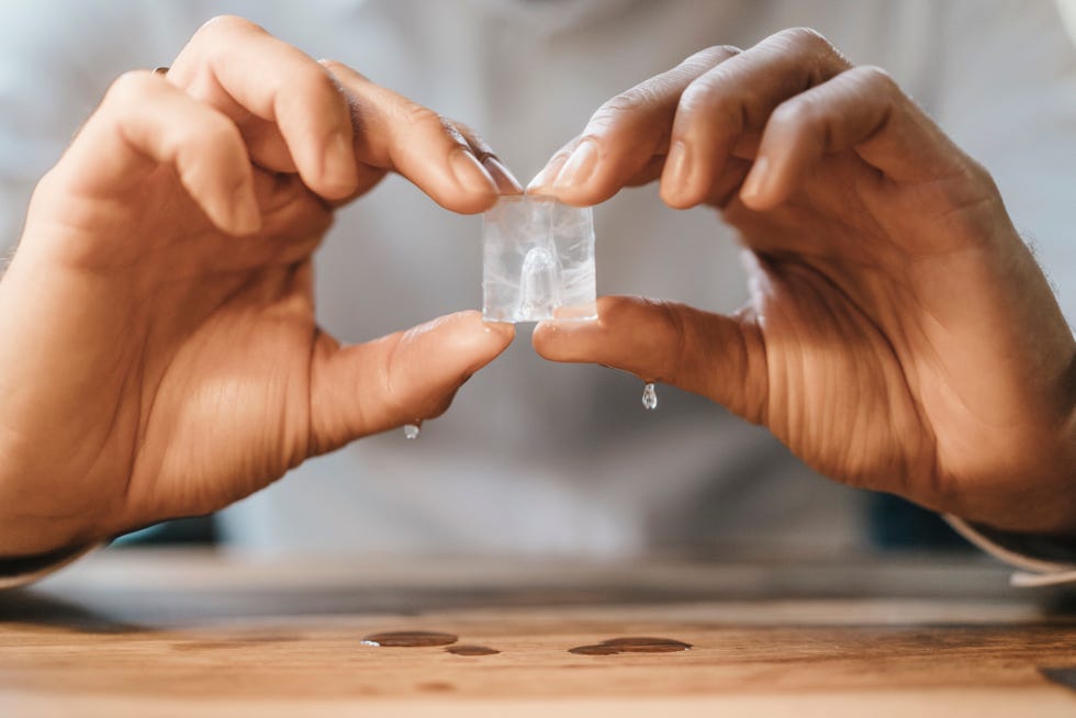 hands of man holding melting ice cube