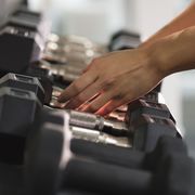 Hands of Mixed Race woman reaching for dumbbells