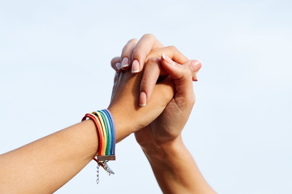 hands of unrecognizable lesbian female couple with lgbt rainbow bracelet