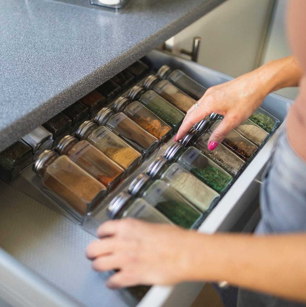 Hands of woman arranging spice jars in kitchen drawer hands of woman arranging spice jars in kitchen drawer