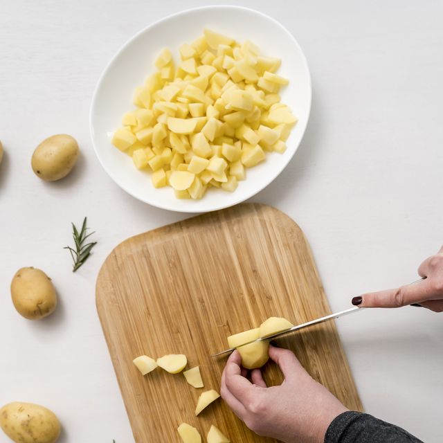 hands of woman chopping potatoes on cutting board