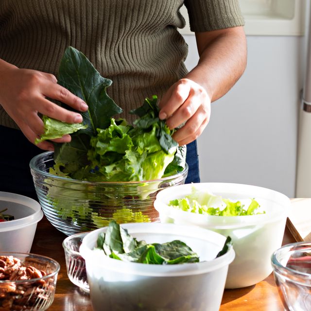 hands of woman mixing lettuce and spinach in a bowl of glass to make a salad