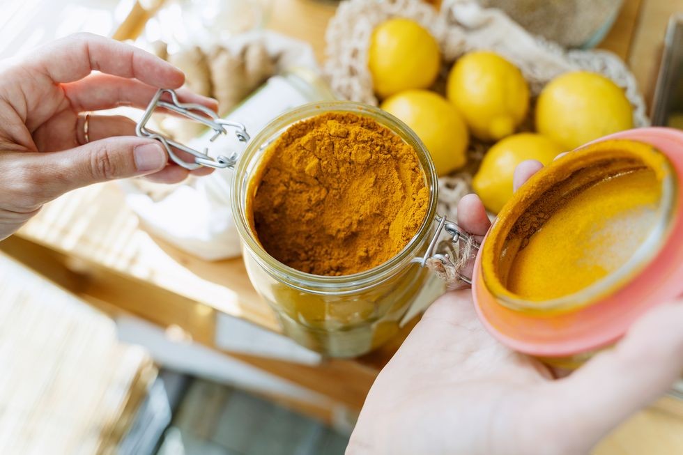 hands of woman with turmeric jar at table