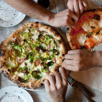 hands reach for naples style pizza