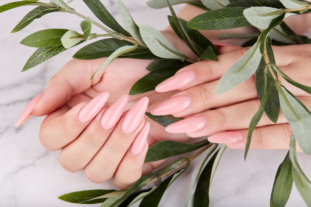 hands with long artificial manicured nails colored with pink nail polish